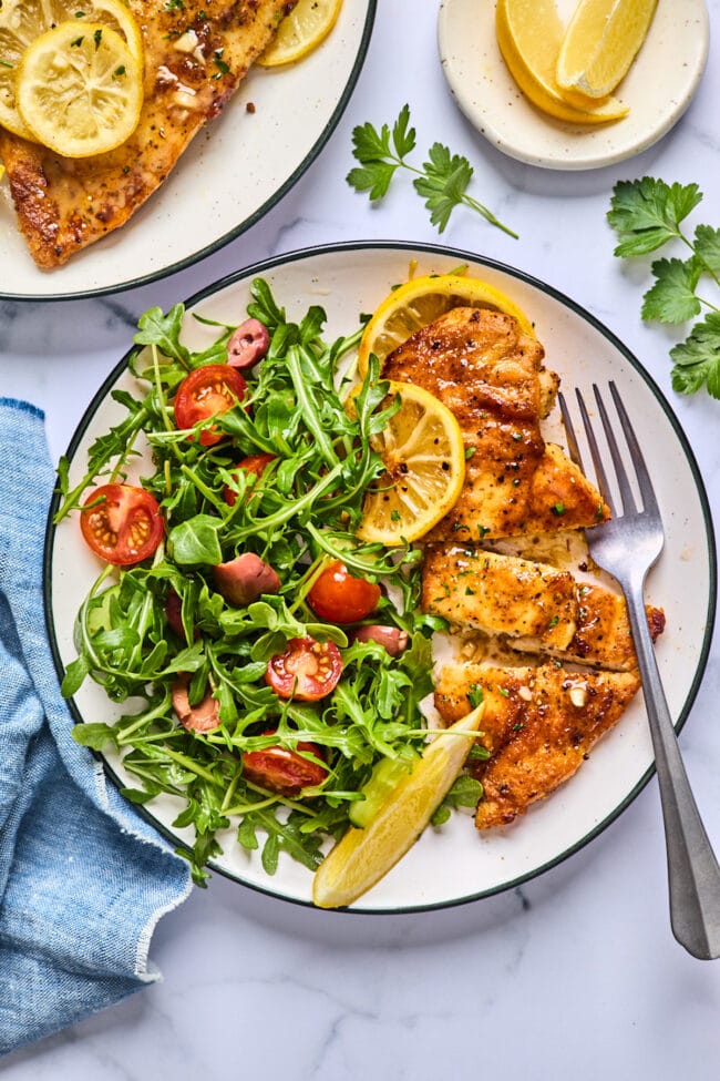 baked lemon butter chicken on plate with salad