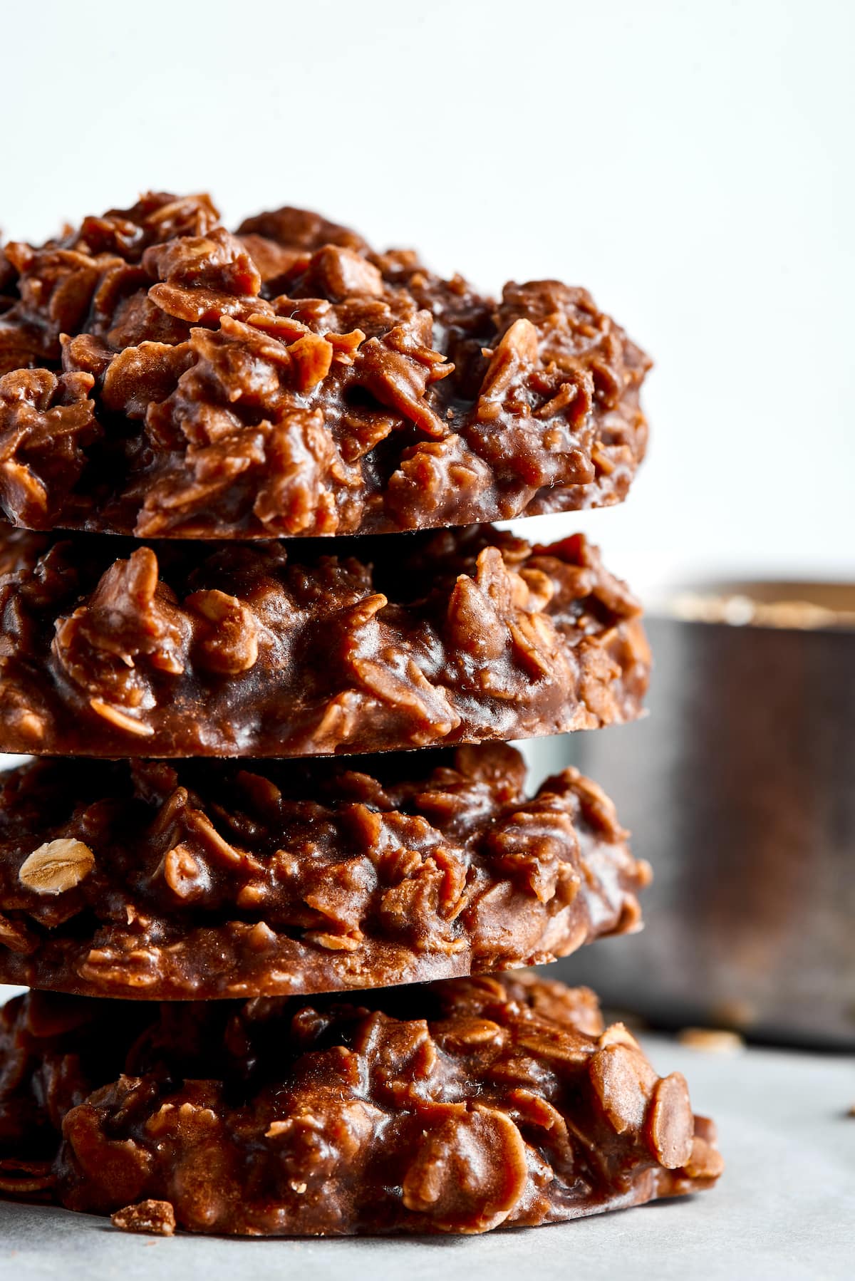 Four no bake cookies stacked on top of each other, with a saucepan in the background